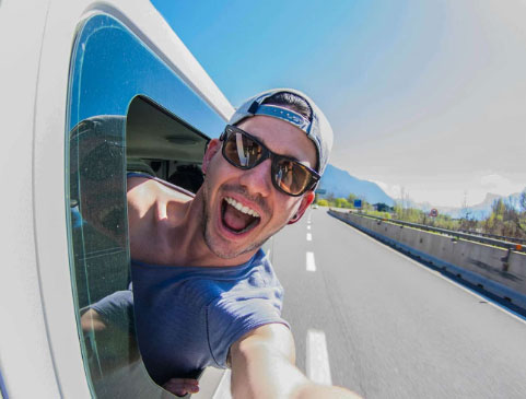 Smiling man in hat and sunglasses sticking his head out the side of an RV