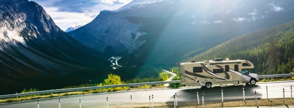 RV traveling on the road with a mountain landscape