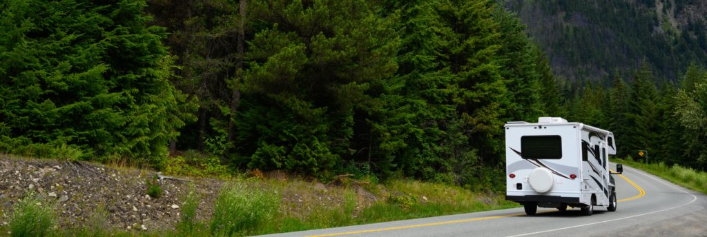 rv driving through the trees and mountains