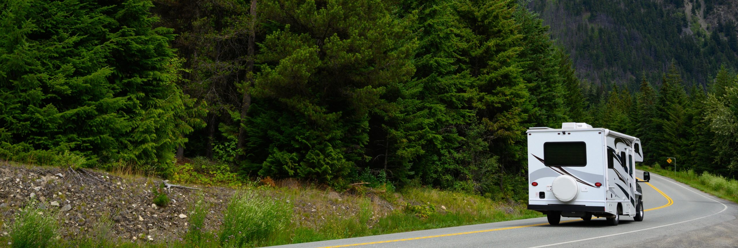 rv driving through the trees and mountains